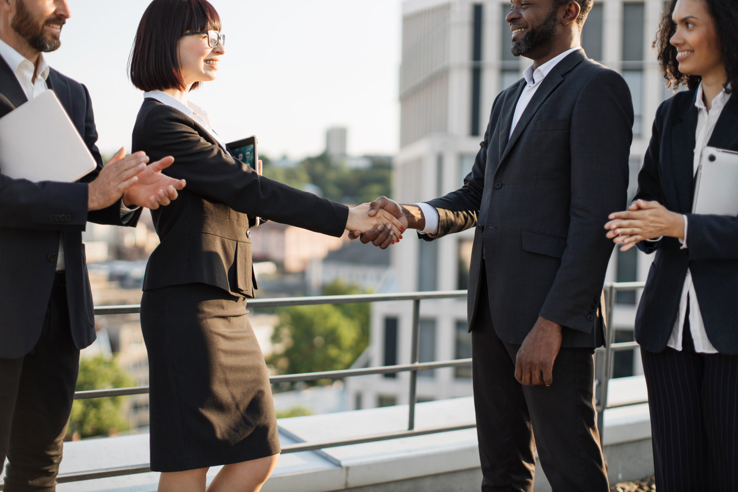 Crop of diverse business people in formal clothes making successful deal and rejoicing cooperation. Caucasian and african american colleagues shaking hands after negotiations. Concept of partnership.